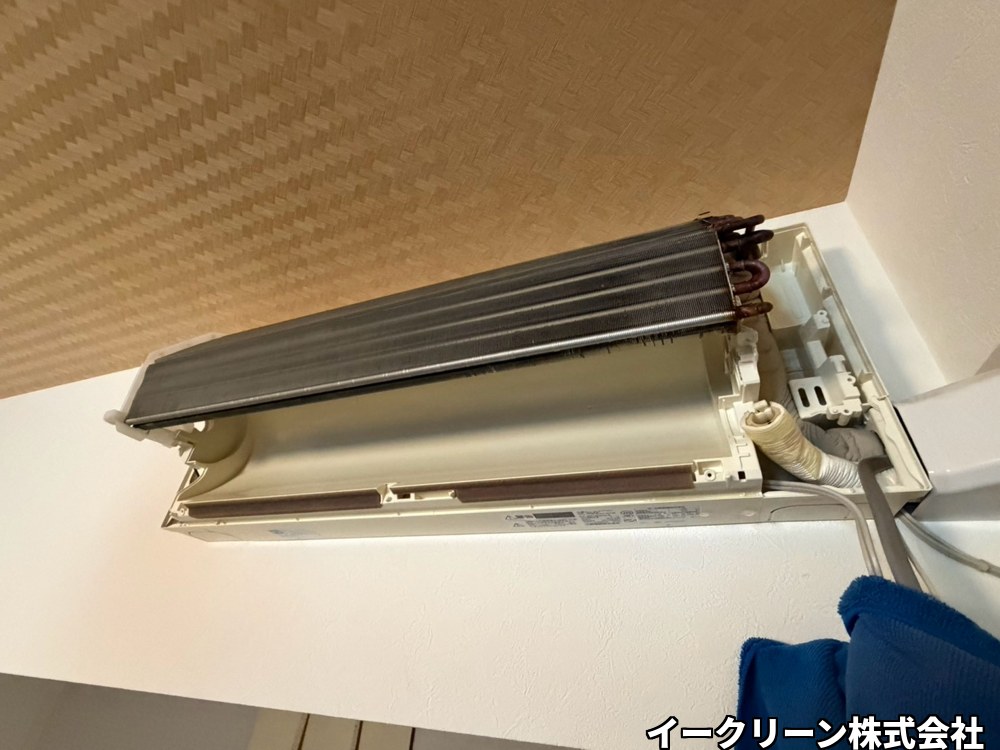 完全分解の作業中。壁に付けたまま熱交換器を手前に起こし、送風ファンとドレンパンを外せる状態にしたエアコン