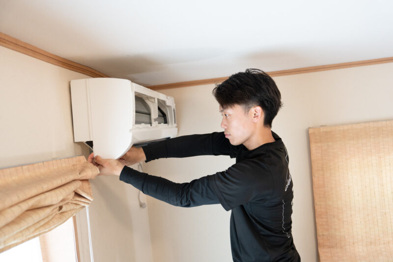 エアコンを分解修理している男性